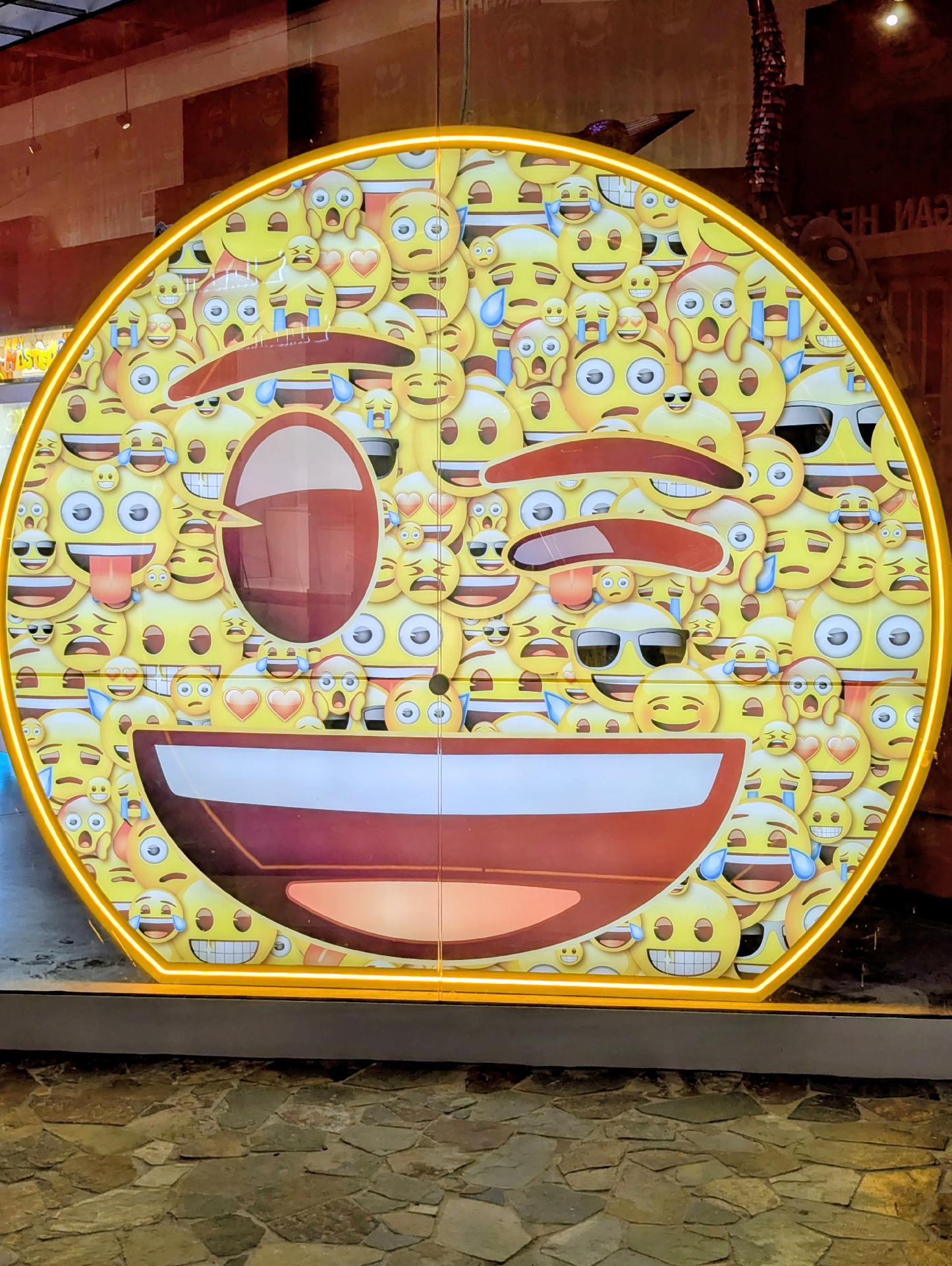 A giant light-up display in the store of a winking-face emoji made up of other, smaller emojis
