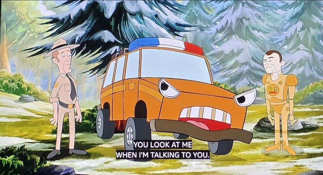 A cartoon in the style of Dudley Do Right showing Jack with a Ranger hat on, his jeep animated with headlight eyes, grill teeth, mouth and tongue. Carl (the car) says, "You look at me when I'm talking to you!" Andy, the android appears as a gold robot similar to Tweekie from Buck Rogers (but full size). They are in a cartoon wooded road with snow covered fir trees.