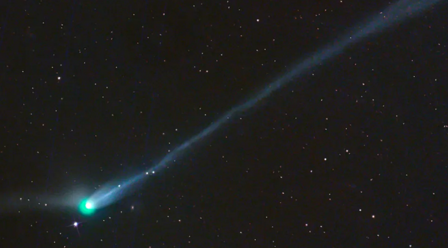 Bright green comet with a glowing nucleus and a long, luminous tail streaking across a star-filled night sky. (Image credit: Gerald Rhemann)