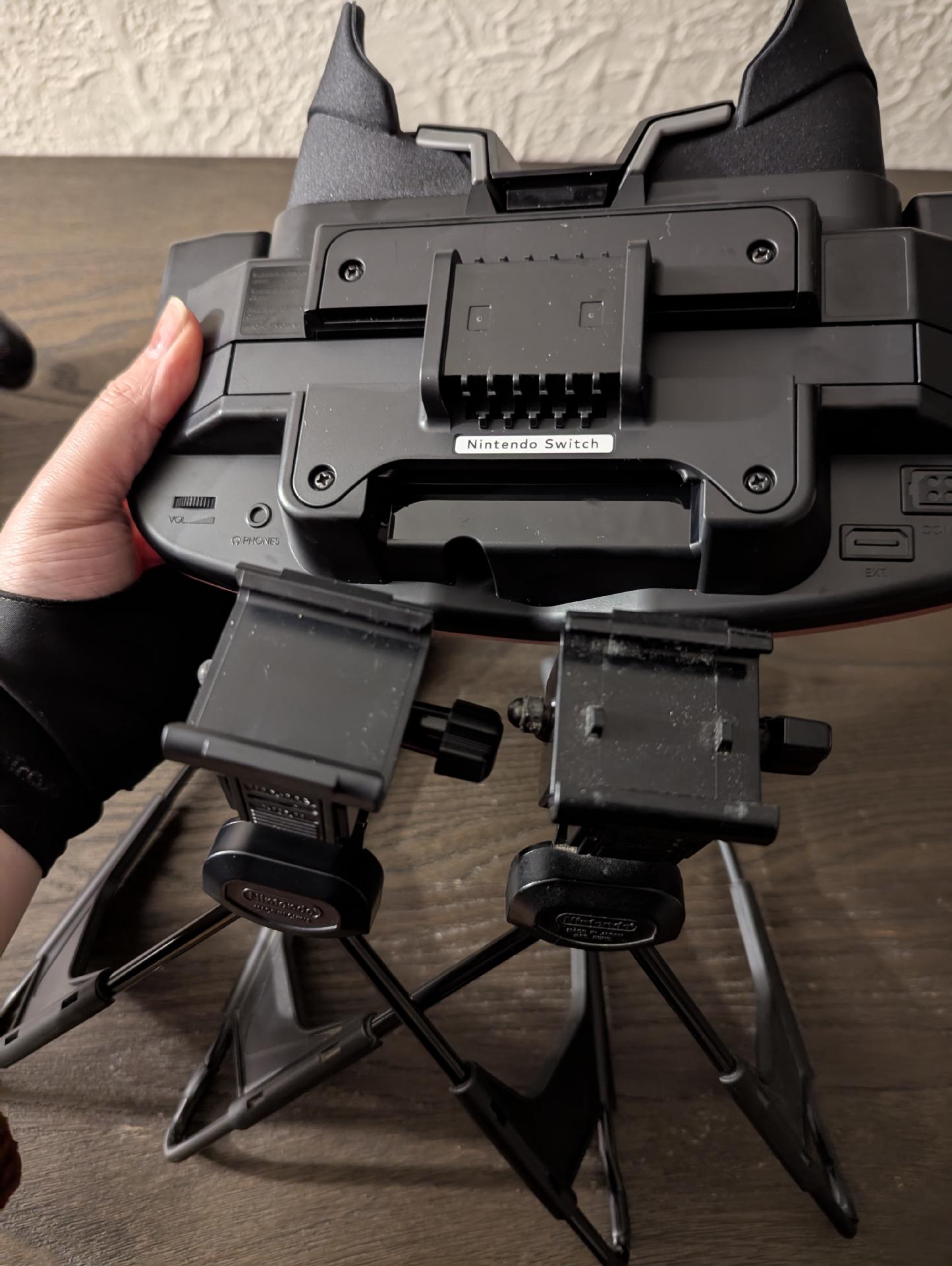 The top of the two Virtual Boy stands, the old one on the right showing the two metal "bumps" I mentioned, compared to the bottom of the new VB accessory which has no spot for the "bump" though you can see where they WOULD be