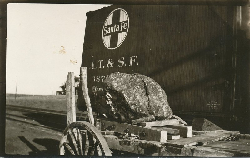 A large meteorite on a cart in front of a Santa Fe boxcar