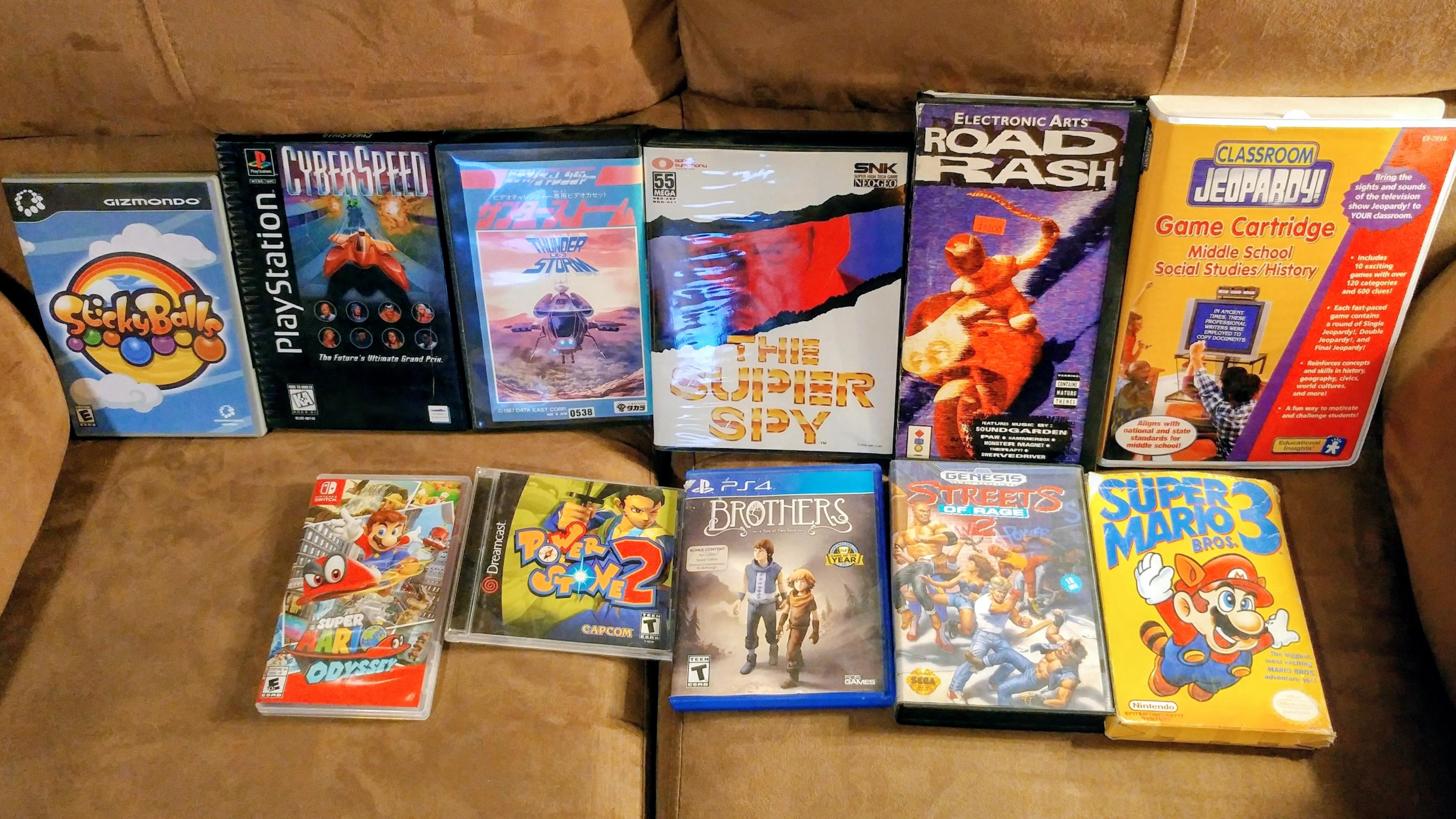 Bottom left to top right:
Switch, Dreamcast, PS4, Genesis, NES, Gizmondo, PlayStation, Video Challenger, Neo Geo, 3DO, and Classroom Jeopardy