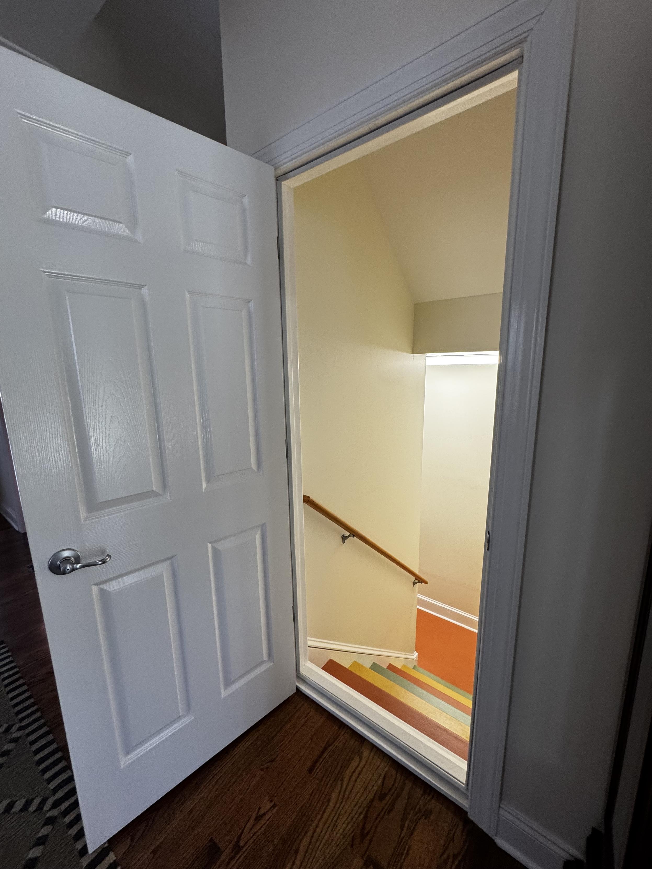 The door, from the main level looking down the stairs.  An oak floor is a contrast to that really quite massive white-painted door sill.  The stairs are painted in one of 3 colors, to help mitigate the trip risk of wooden stairs.  But I still have this stupid thing at the top.