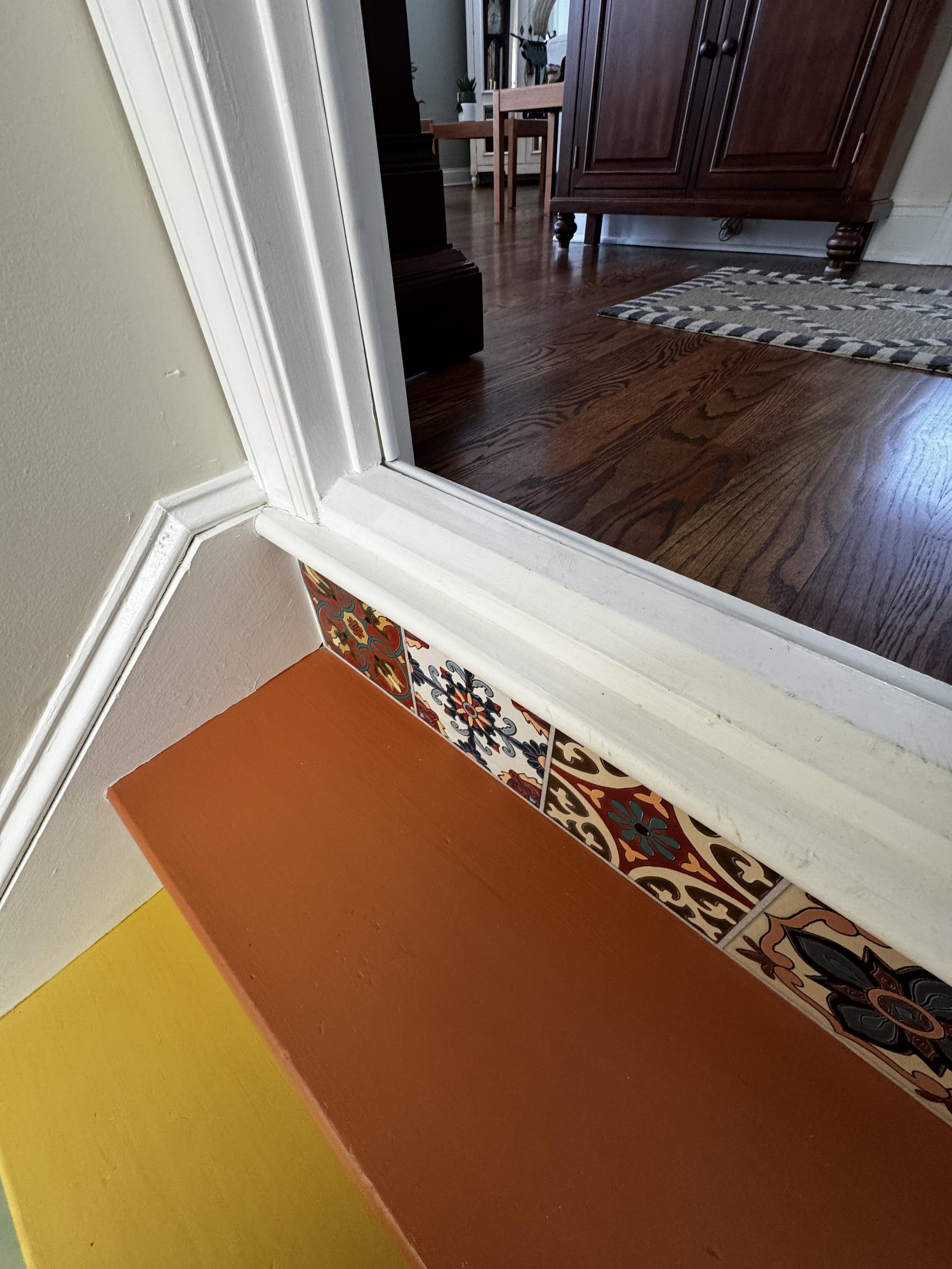 This photo is shooting from the stairs back up to the main level.  I think the white-painted stair nose is probably at the height one would actually want for this first step, but everything else has been layered on top of it.  Normal interior doors, aren't framed like this, clearly.

How would one go about fixing this issue?  Many thanks.