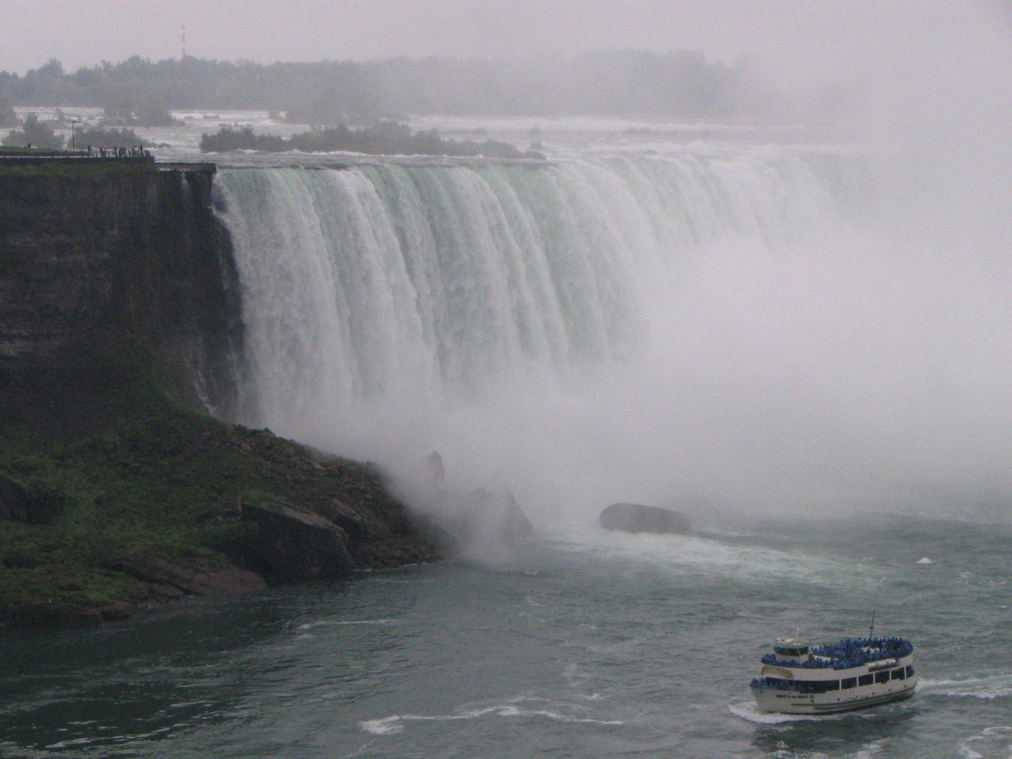 A photo of the horseshoe falls, almost always shrouded in mist, with one of the sight-seeing boats coming up toward the bottom of the waterfall.  An enormous volume of water coming over the top of the falls (did you know they actually dial the flow down at night?) and everyone on that boat is blue, as I imagine those are loaner raincoats for the tourists.

I was happy to look from a longer, drier distance.