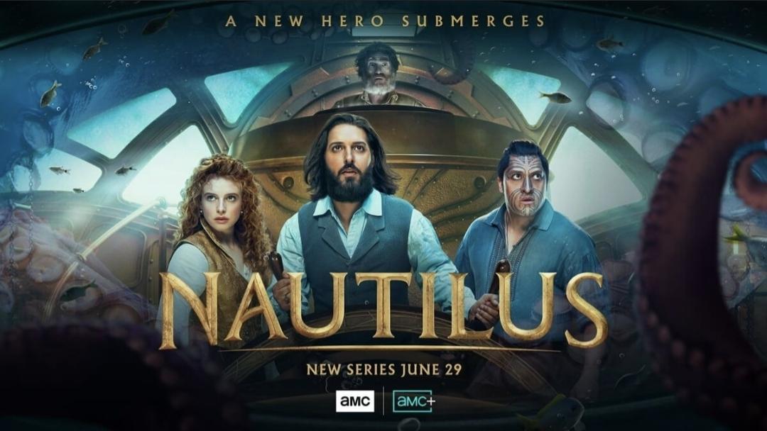 Shows the inside of the Steampunkish submarine. Shazad Latif has his hands on the ship's wheel. He looks excited and happy at what he's seeing. Beside him is Georgia Flood (a redheaded woman looking determined) and Tyrone Ngatai a Maori man looking  like he sees something dangerous. Behind and above Shazad we see  an older man. I think the actor is Thierry Fremont. Outside the ship flanking on both sides we see a giant octopus' tentacles. 
Text reads:
A new hero submerges
Nautilus
New series June 29
AMC AMC+