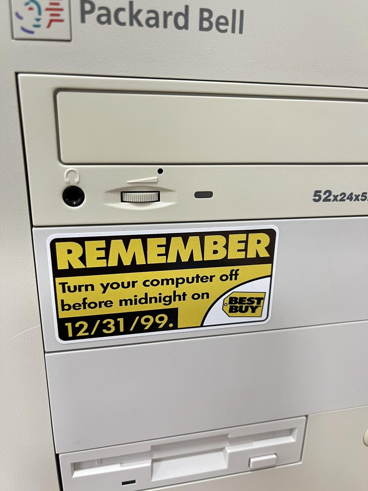 A Packard Bell computer with a Best Buy sticker on it that reads “REMEMBER: Turn your computer off before midnight on 12/31/99.”