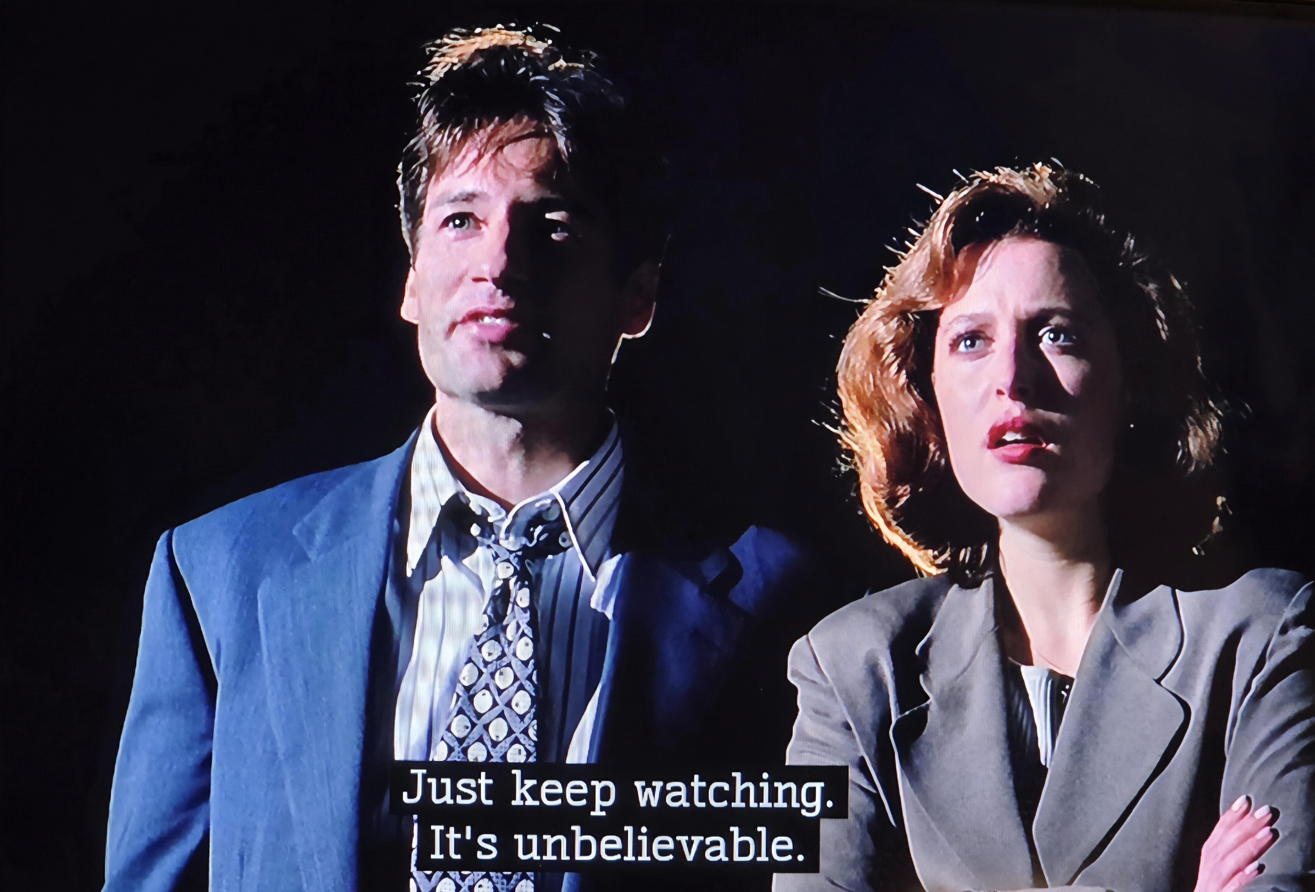 My two favorite fictional FBI agents: Fox Mulder and Dana Scully in X-Files s.1 e.2. they are looking up at the night sky. Dana looks confused. Mulder looks pleased. Both wearing business suits. Dama has her arms crossed. 
Mulder tells Dana, "Just keep watching. It's unbelievable."