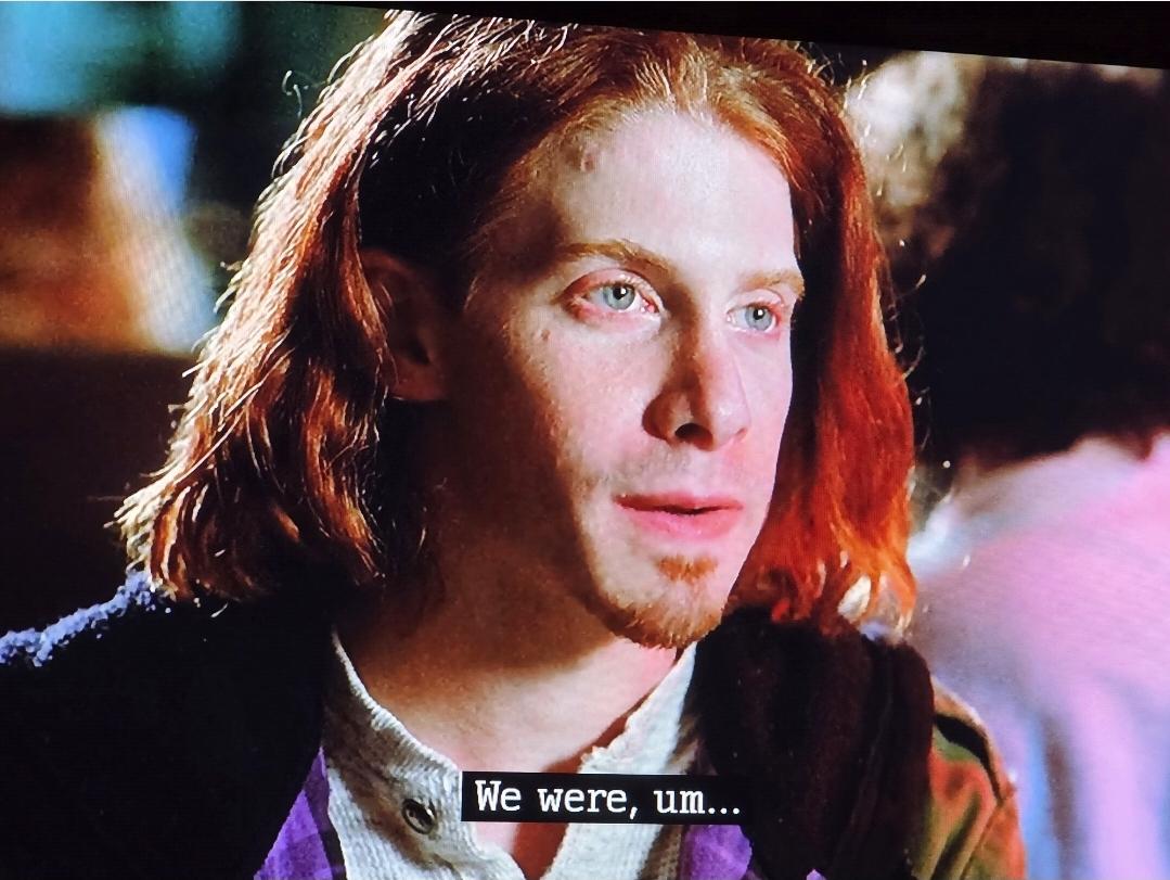 A young Seth Green (early 20s) with shoulder length red hair and goatee.  He says l, "We were, um..."