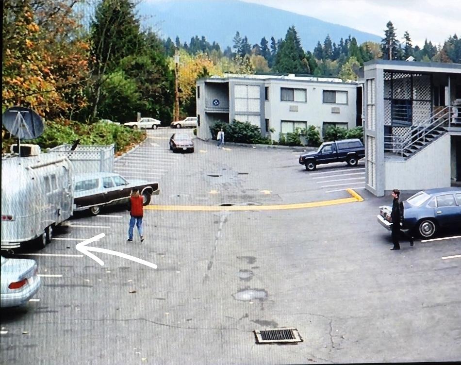 Max Fenig is walking toward a silver 1960s style airstream trailer pulled by an old woodie station wagon. Mulder is standing by his motel walking towards the trailer.