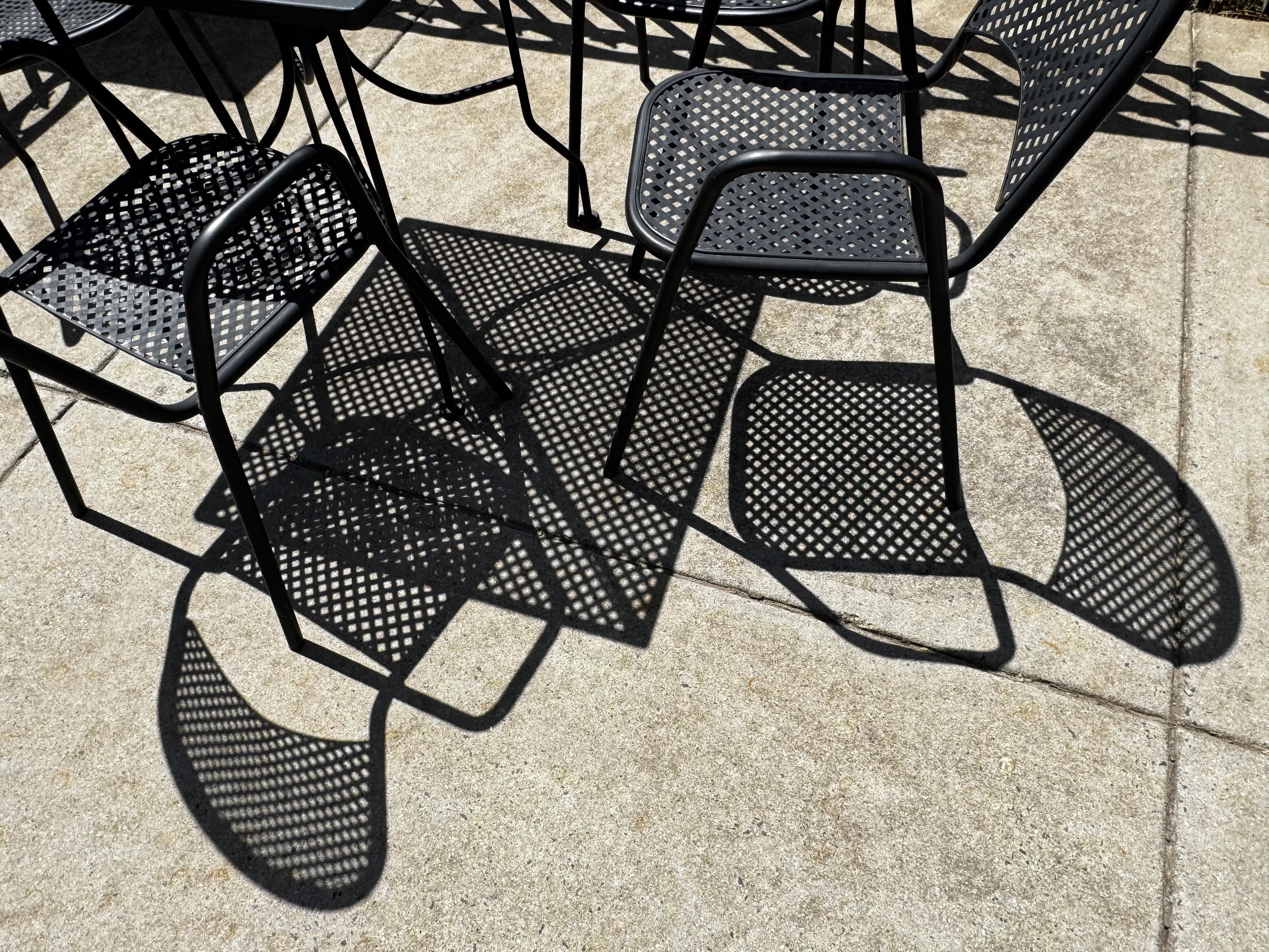 The shadows of these metal mesh chairs and table were just too much to miss.  Happily no one was on the patio with us.  It made me think of Mondrian, but without the color, somehow.  Vaguely modern art-y.

The black furniture is hard to distinguish from their very clear and sharp black shadows, which all seem to overlap.