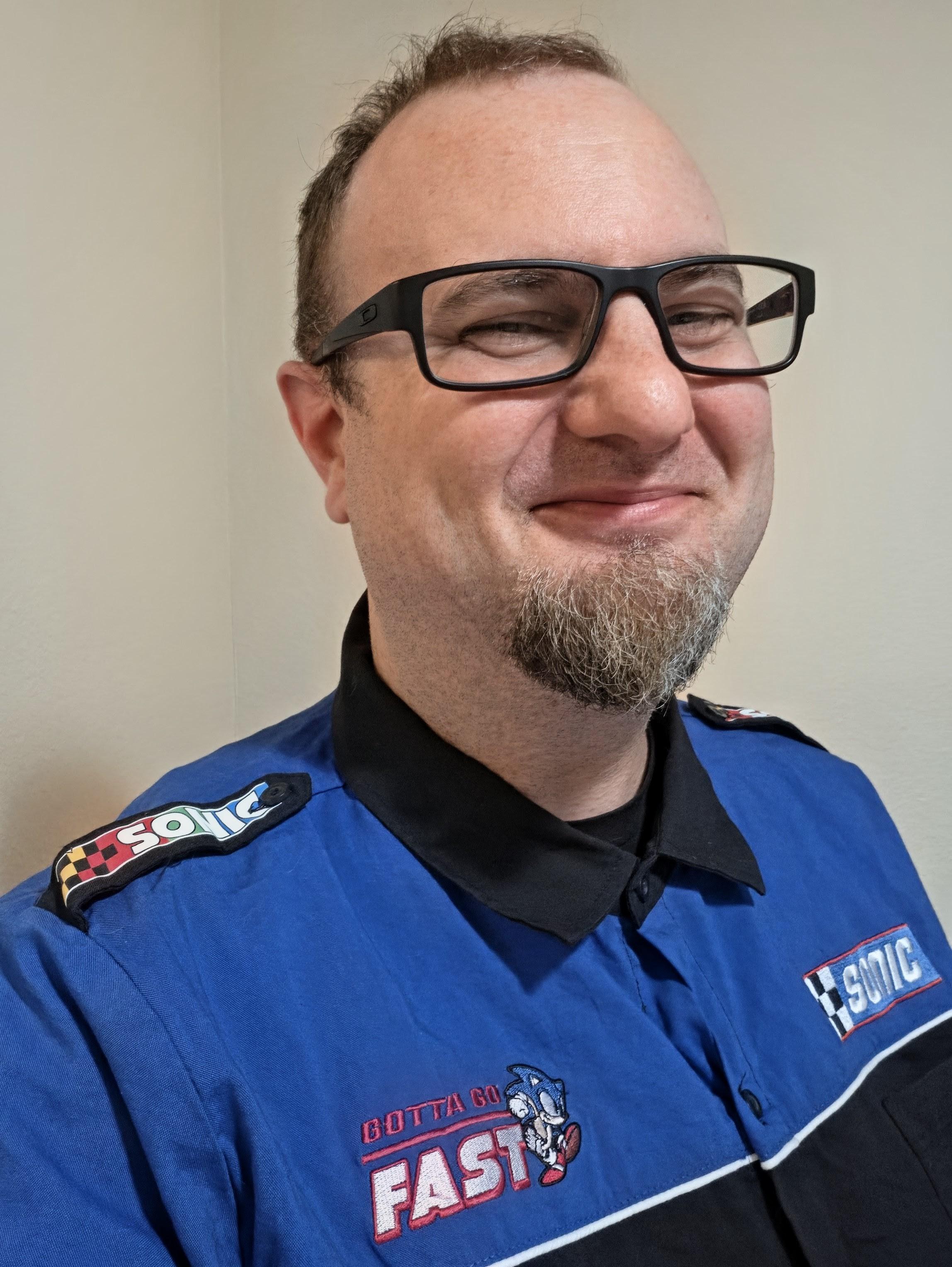 Sonic racing pit shirt with short sleeves. Shoulders say "Sonic" and so does left breast. Right says "gotta go fast." Top of shirt is blue above the breast. Rest is black.