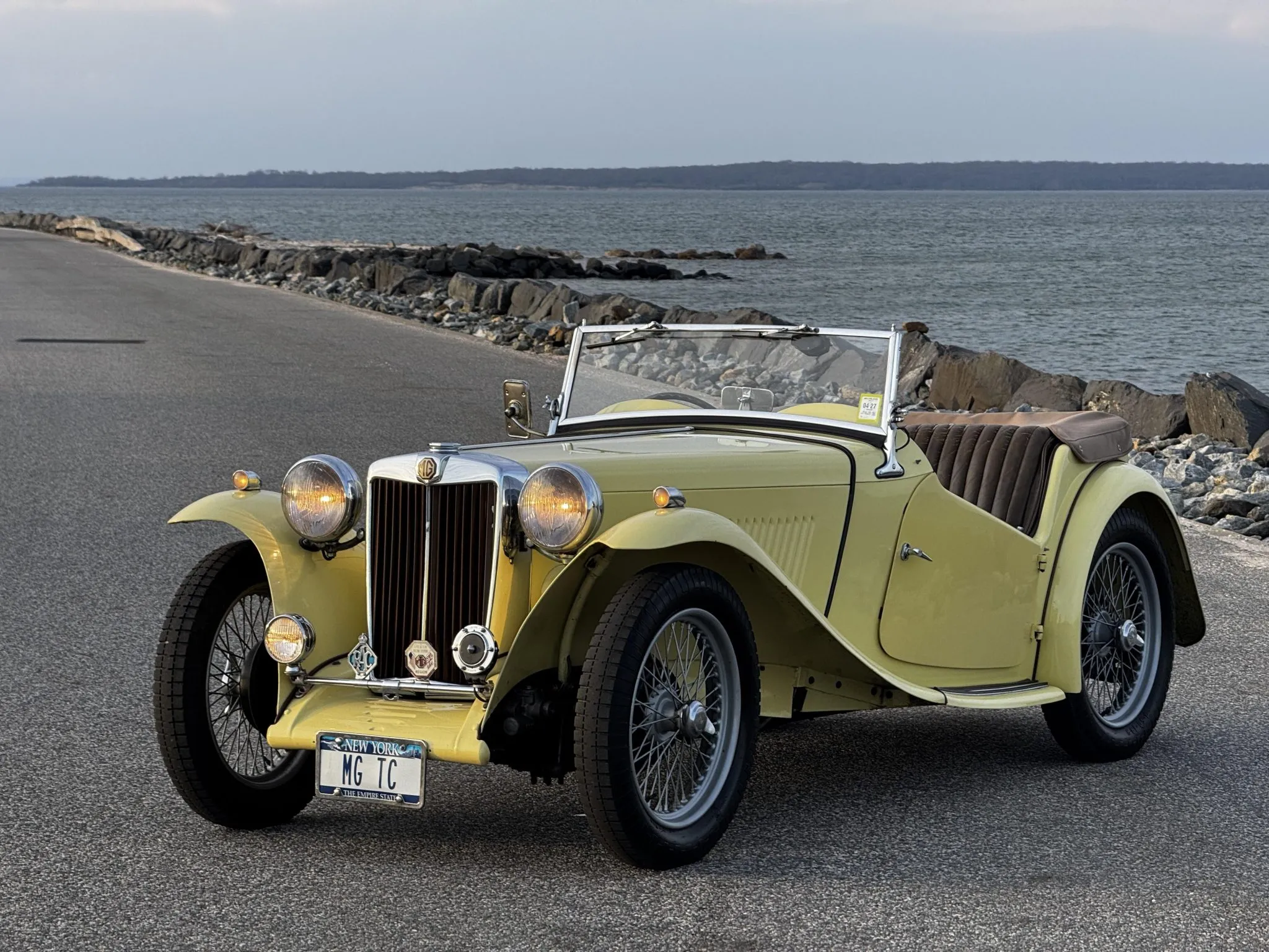 This 1949 MG TC is finished in Primrose over brown leather and is powered by a 1,250cc inline-four paired with a four-speed manual transmission. Features include a beige soft top, side curtains, and tonneau cover as well as 19″ knock-off wire wheels, a badge bar, a driving light, Jaeger instrumentation, and dual SU carburetors.